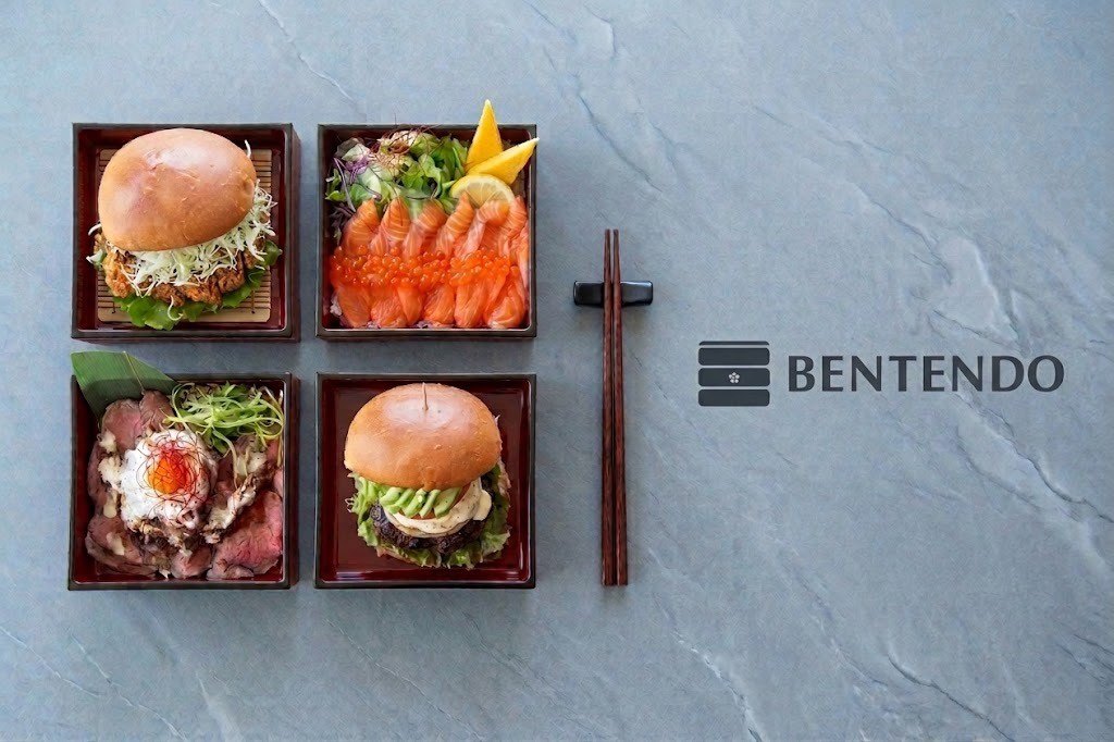 Four Bentendo boxes laid out on a stone surface with chopsticks.